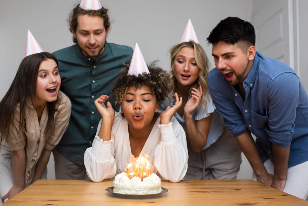 One of group of friends blow up the candle that is in the cake